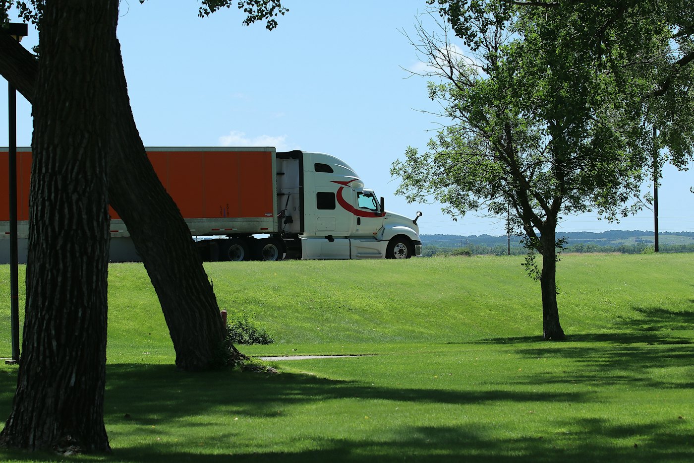 Semi truck and trailer parked beside a grassy field